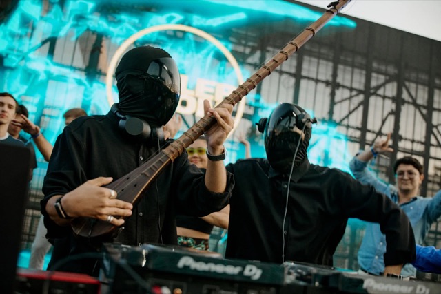 Masked artists with electronic and traditional instruments
